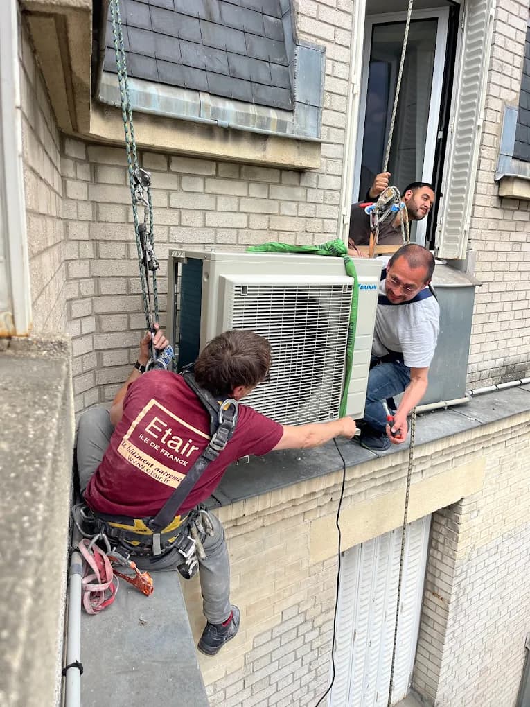 Techniciens RR Énergies installant un groupe extérieur de climatisation en hauteur sur une façade parisienne