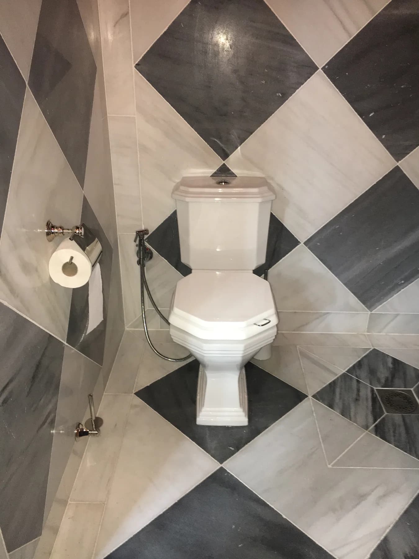 WC dans des toilettes au carrelage marbre noir et blanc